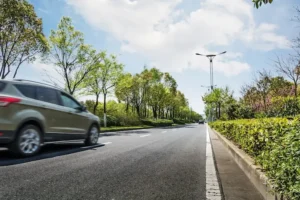 Voiture en mouvement sur une route bordée d'arbres, illustrant le calcul des frais kilométriques professionnels