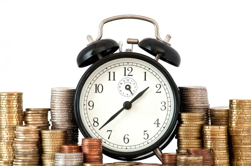 réveil et pièces de monnaie illustrant la notion de temps et d'argent